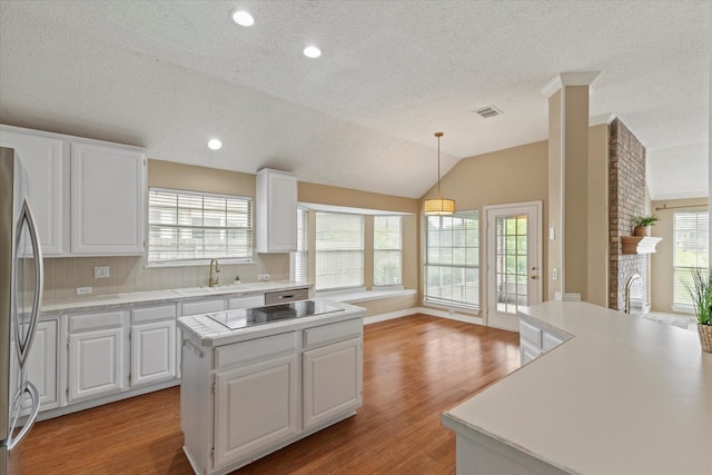 11200 Williamsburg Ln, Frisco, TX 75035 - kitchen featuring freestanding refrigerator, black electric cooktop, a center island, a textured ceiling, and light countertops