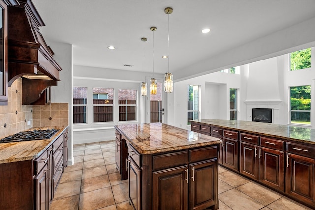 1228 Copano Dr, Allen, TX 75013 - kitchen with black gas stovetop, a center island, tasteful backsplash, light stone countertops, and a chandelier