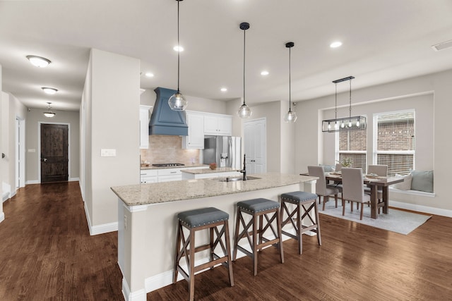 2402 Wilson Dr, Anna, TX 75409 - kitchen with stainless steel refrigerator with ice dispenser, premium range hood, dark wood-style floors, a kitchen island with sink, and recessed lighting