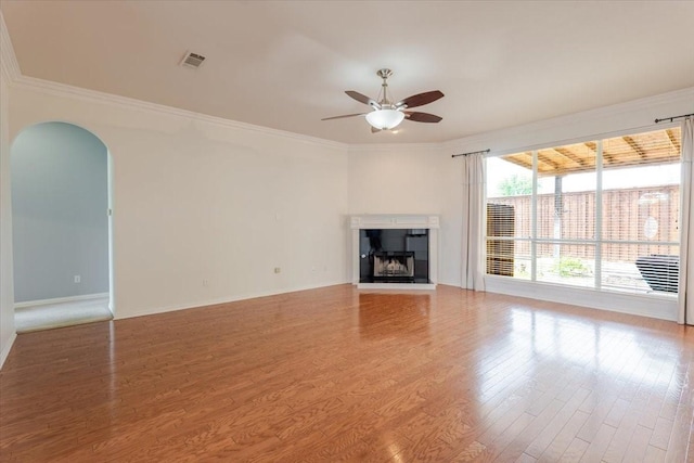 316 Cottonwood Trl, Shady Shores, TX 76208 - unfurnished living room with a ceiling fan, crown molding, arched walkways, wood finished floors, and a tile fireplace
