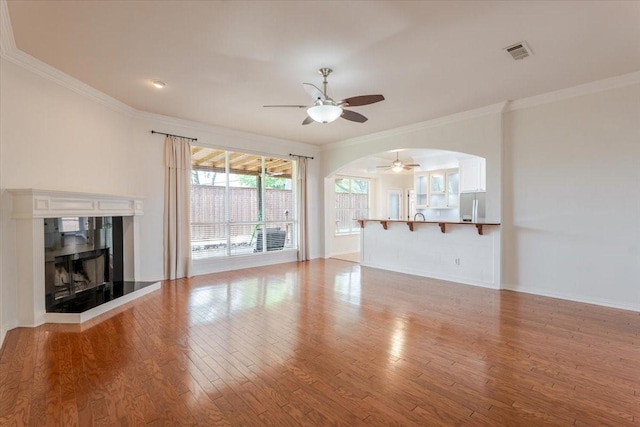 316 Cottonwood Trl, Shady Shores, TX 76208 - unfurnished living room featuring a ceiling fan, ornamental molding, wood finished floors, arched walkways, and a fireplace with raised hearth