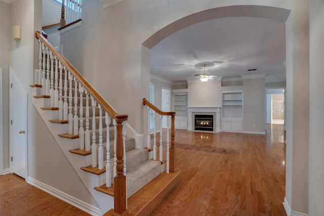 9 Park Place Ct, Wichita Falls, TX 76302 - stairway featuring a ceiling fan, wood finished floors, built in features, arched walkways, and a fireplace with flush hearth