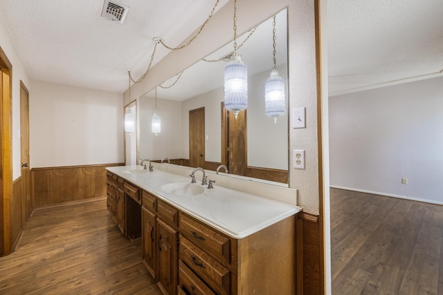 4508 Ramsgate Ct, Arlington, TX 76013 - bathroom featuring a textured ceiling, wood finished floors, double vanity, wainscoting, and wooden walls