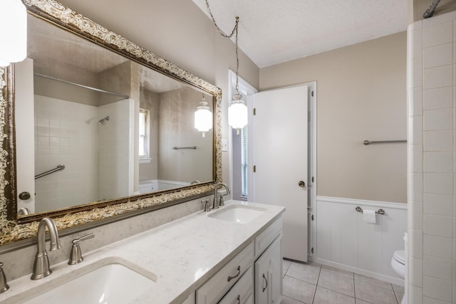 4508 Ramsgate Ct, Arlington, TX 76013 - bathroom featuring toilet, double vanity, tile patterned floors, a tile shower, and wainscoting
