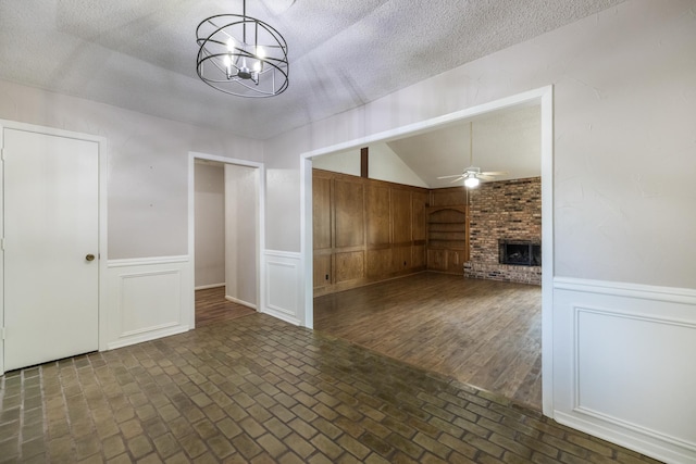 4508 Ramsgate Ct, Arlington, TX 76013 - unfurnished living room featuring a fireplace, lofted ceiling, a ceiling fan, a textured ceiling, and a chandelier