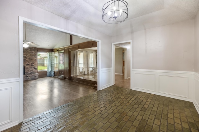4508 Ramsgate Ct, Arlington, TX 76013 - spare room featuring a textured ceiling, a chandelier, a wainscoted wall, brick patterned flooring, and ceiling fan