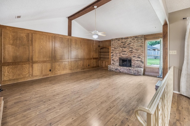 4508 Ramsgate Ct, Arlington, TX 76013 - unfurnished living room featuring wood finished floors, a ceiling fan, wood walls, a brick fireplace, and a textured ceiling