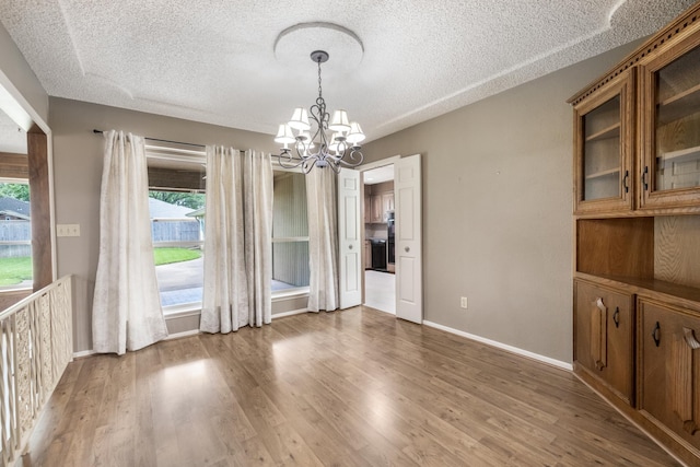 4508 Ramsgate Ct, Arlington, TX 76013 - unfurnished dining area featuring a textured ceiling, a chandelier, light wood-type flooring, and baseboards
