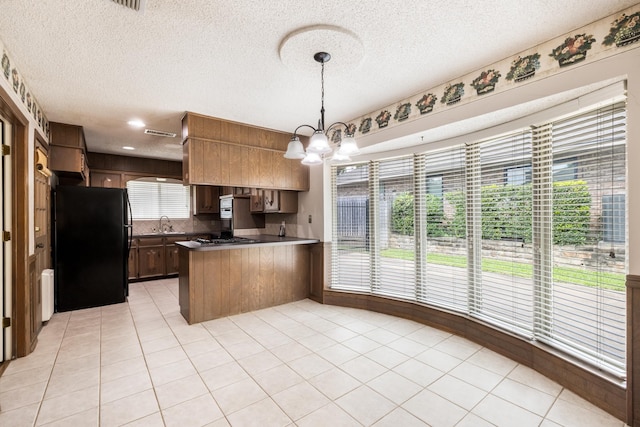 4508 Ramsgate Ct, Arlington, TX 76013 - kitchen featuring freestanding refrigerator, a peninsula, a chandelier, a textured ceiling, and light tile patterned floors