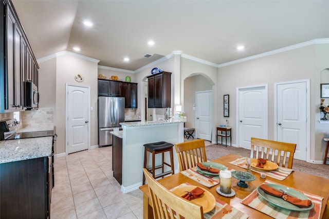 11408 Aquilla Dr, Frisco, TX 75036 - dining room featuring arched walkways, recessed lighting, ornamental molding, light tile patterned floors, and baseboards