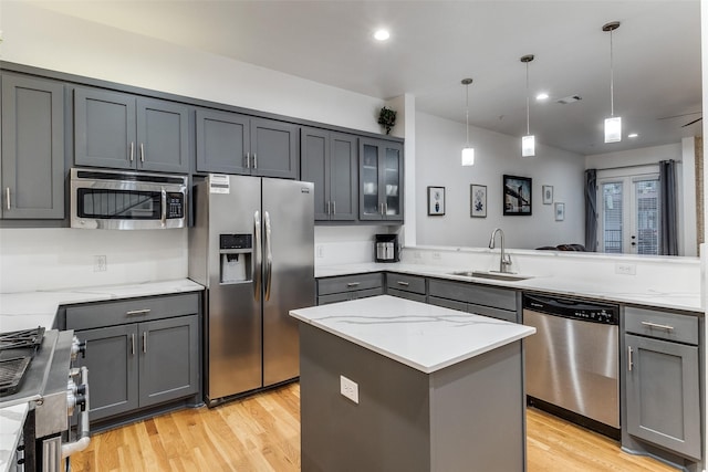 3320 Douglas Ave Unit C, Dallas, TX 75219 - kitchen featuring appliances with stainless steel finishes, a sink, gray cabinetry, light wood finished floors, and light stone counters