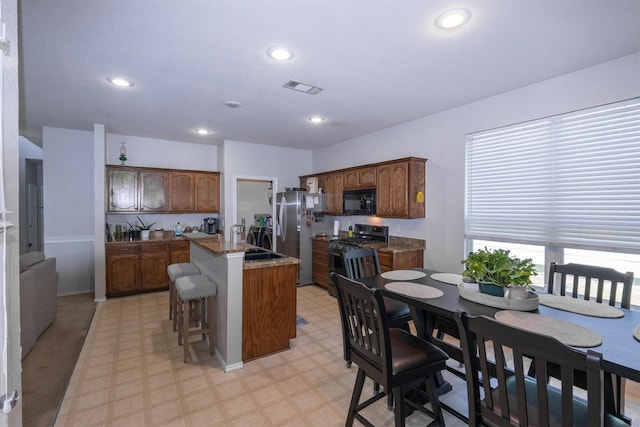 10940 Dillon St, Fort Worth, TX 76179 - kitchen with appliances with stainless steel finishes, light floors, a kitchen island, a breakfast bar area, and a sink
