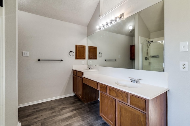 1721 Chapman Dr, Mesquite, TX 75149 - bathroom featuring lofted ceiling, double vanity, wood finished floors, a stall shower, and baseboards