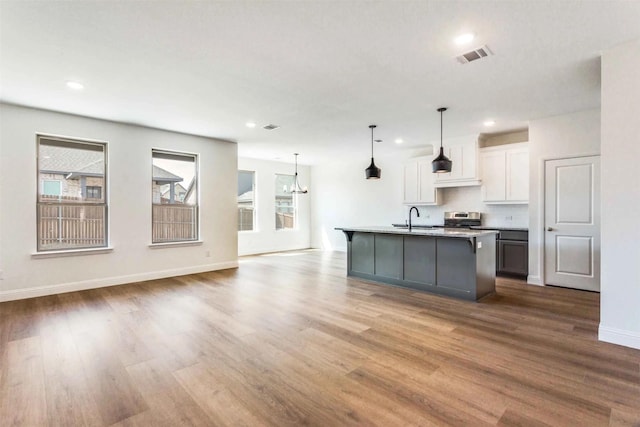 514 Hillcrest Cir, Justin, TX 76247 - kitchen with a sink, stainless steel range, dark wood finished floors, white cabinetry, and an island with sink