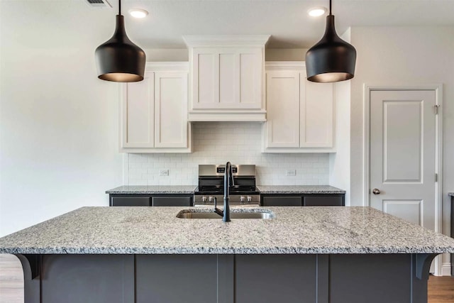 514 Hillcrest Cir, Justin, TX 76247 - kitchen featuring light stone countertops, stainless steel range with electric cooktop, a kitchen island with sink, tasteful backsplash, and a sink