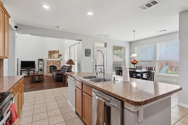 403 Elmcrest Ct, Forney, TX 75126 - kitchen featuring stainless steel appliances, a sink, a brick fireplace, light tile patterned floors, and hanging light fixtures