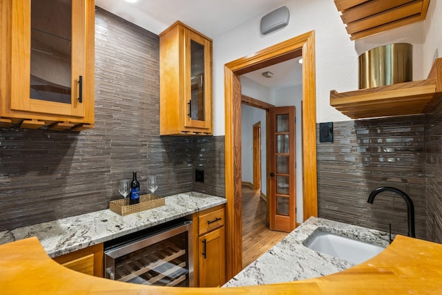 8907 Meadowknoll Dr, Dallas, TX 75243 - kitchen featuring beverage cooler, a sink, backsplash, wood finished floors, and light stone counters