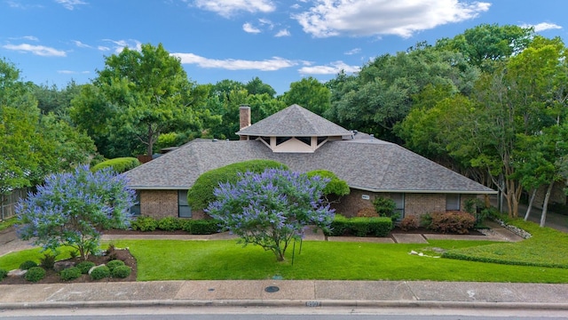 8907 Meadowknoll Dr, Dallas, TX 75243 - view of front facade with a chimney, a front lawn, a shingled roof, and brick siding