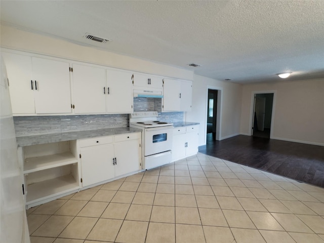 921 Longino St, Sulphur Springs, TX 75482 - kitchen with electric stove, under cabinet range hood, decorative backsplash, a textured ceiling, and white cabinetry