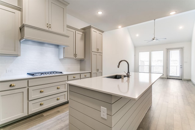 135 Claire Dr, Trophy Club, TX 76262 - kitchen with a sink, stainless steel gas stovetop, gray cabinets, light wood-type flooring, and tasteful backsplash