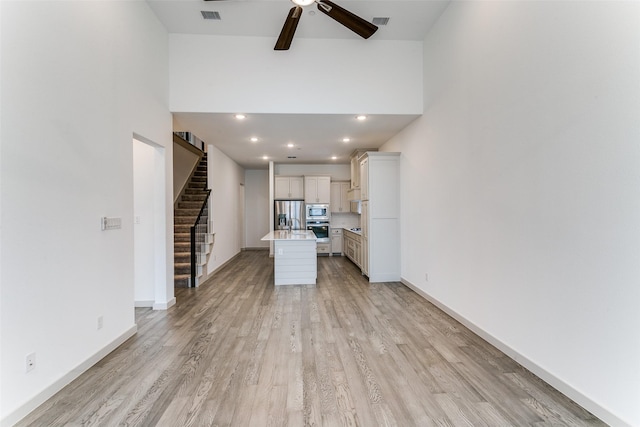 135 Claire Dr, Trophy Club, TX 76262 - unfurnished living room with a ceiling fan, light wood finished floors, stairs, a towering ceiling, and baseboards