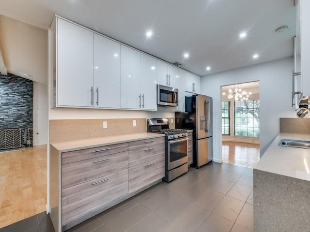 3414 Country Club Rd, Pantego, TX 76013 - kitchen featuring appliances with stainless steel finishes, white cabinetry, light countertops, light tile patterned floors, and a chandelier