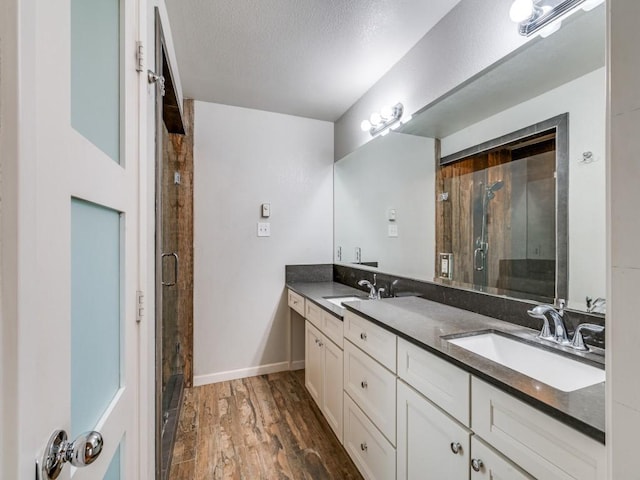 3414 Country Club Rd, Pantego, TX 76013 - bathroom with double vanity, wood finished floors, a stall shower, baseboards, and a textured ceiling