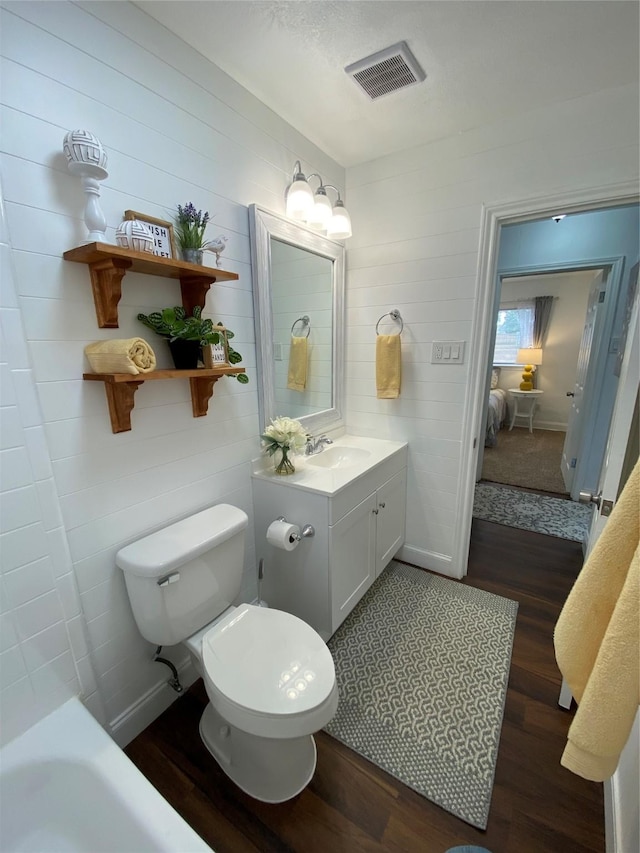 4313 Windsor Dr, Garland, TX 75042 - full bath with wood finished floors, vanity, toilet, and a tub