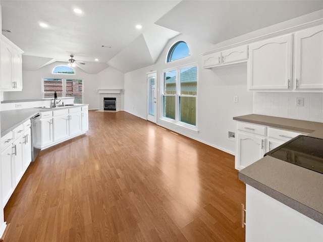 4162 Stone Hollow Way, Fort Worth, TX 76040 - kitchen with stainless steel dishwasher, a ceiling fan, vaulted ceiling, a tile fireplace, and a sink