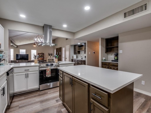 7015 Cloverglen Dr, Dallas, TX 75249 - kitchen featuring stainless steel appliances, island exhaust hood, light wood-style flooring, vaulted ceiling, and open shelves