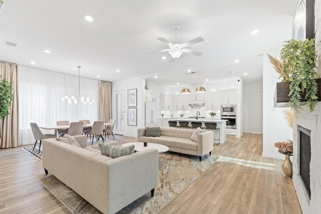 8509 Barnbougle Dunes Dr, Mckinney, TX 75070 - living room featuring ceiling fan, light wood-style floors, a chandelier, a fireplace, and recessed lighting