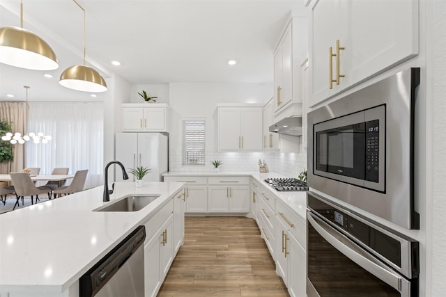 8509 Barnbougle Dunes Dr, Mckinney, TX 75070 - kitchen featuring appliances with stainless steel finishes, a sink, light wood-style floors, tasteful backsplash, and light countertops