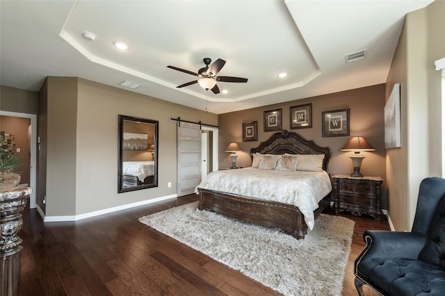 4426 Mineral Creek Trl, Celina, TX 75078 - bedroom featuring a tray ceiling, a barn door, dark wood-style flooring, baseboards, and recessed lighting