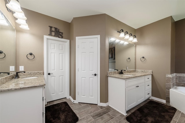 4426 Mineral Creek Trl, Celina, TX 75078 - bathroom with two vanities, a garden tub, wood tiled floors, and baseboards