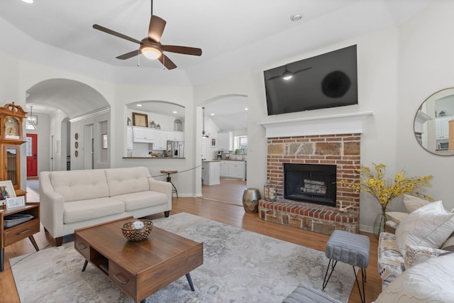 8228 Shady Valley Dr, Benbrook, TX 76116 - living room featuring a ceiling fan, light wood finished floors, a fireplace with raised hearth, arched walkways, and recessed lighting