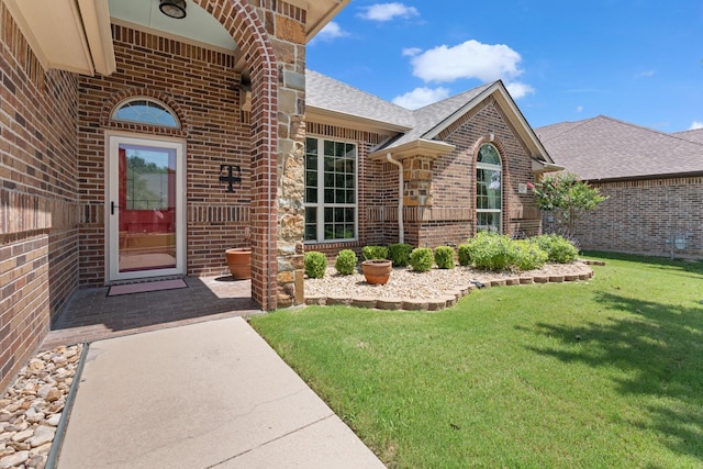 8228 Shady Valley Dr, Benbrook, TX 76116 - view of exterior entry with brick siding, a shingled roof, and a yard