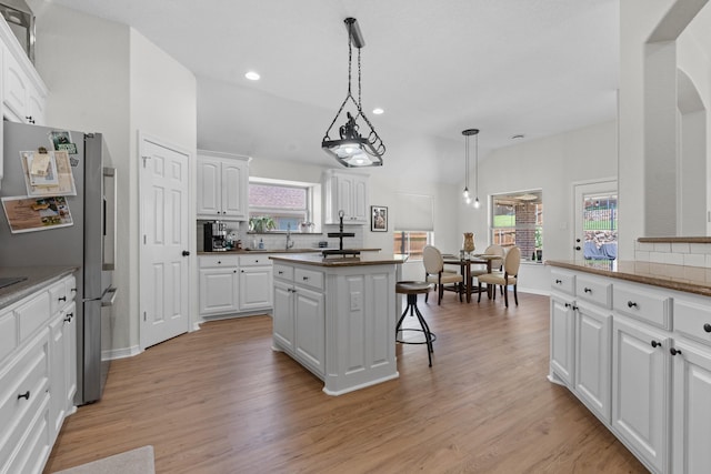 8228 Shady Valley Dr, Benbrook, TX 76116 - kitchen featuring backsplash, a center island, a kitchen bar, white cabinetry, and freestanding refrigerator