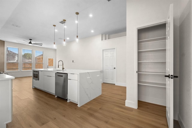 5809 Hidden Pine Ln, Mckinney, TX 75070 - kitchen featuring stainless steel dishwasher, a sink, ceiling fan, light wood-type flooring, and a kitchen island with sink