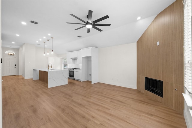 5809 Hidden Pine Ln, Mckinney, TX 75070 - unfurnished living room featuring a large fireplace, ceiling fan, recessed lighting, light wood-style floors, and vaulted ceiling