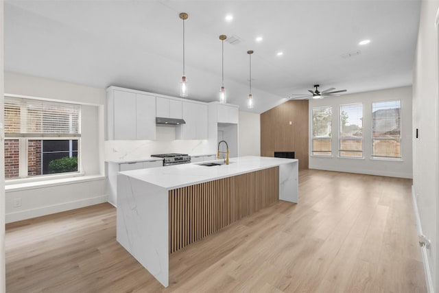 5809 Hidden Pine Ln, Mckinney, TX 75070 - kitchen featuring gas stove, a sink, under cabinet range hood, white cabinetry, and modern cabinets