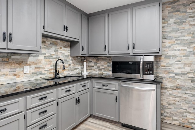 1327 Whispering Springs Dr, Tool, TX 75143 - kitchen with stainless steel appliances, a sink, gray cabinets, backsplash, and dark stone countertops