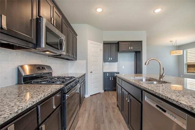 2151 Slow Stream Dr, Royse City, TX 75189 - kitchen with appliances with stainless steel finishes, a sink, light stone counters, light wood-style floors, and dark brown cabinets