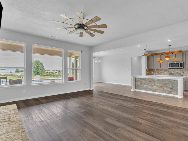 1013 Northern Oaks Ct, Springtown, TX 76082 - unfurnished living room with ceiling fan, wood finished floors, a sink, baseboards, and a chandelier