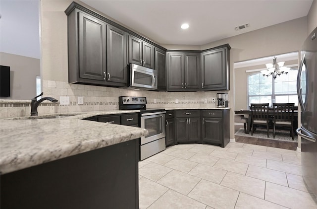 606 Brandt St, Grandview, TX 76050 - kitchen with appliances with stainless steel finishes, a chandelier, a sink, light stone counters, and backsplash
