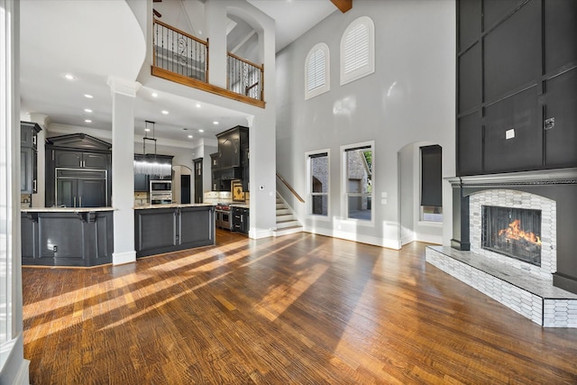 1229 Manchester Dr, Mclendon Chisholm, TX 75032 - unfurnished living room featuring baseboards, dark wood-style flooring, a stone fireplace, a high ceiling, and recessed lighting