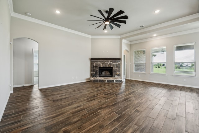13609 Summer Moon Trl, Ponder, TX 76259 - unfurnished living room featuring ceiling fan, arched walkways, a stone fireplace, dark wood-style floors, and ornamental molding