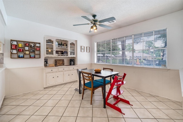 1715 Venetian Cir, Arlington, TX 76013 - dining room featuring healthy amount of natural light, a textured ceiling, a wainscoted wall, ceiling fan, and light tile patterned floors