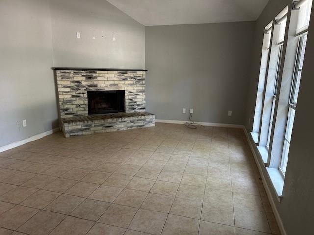 1042 Kim Ln, Mesquite, TX 75149 - unfurnished living room with vaulted ceiling, a fireplace, tile patterned floors, and baseboards