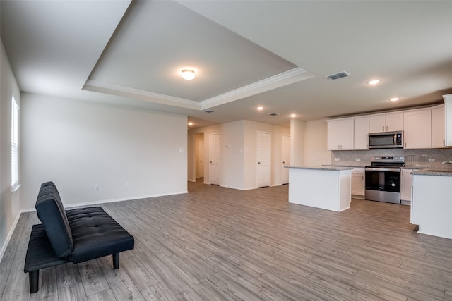 1609 Silas Dr, Forney, TX 75126 - kitchen featuring stainless steel appliances, a tray ceiling, open floor plan, a center island, and ornamental molding