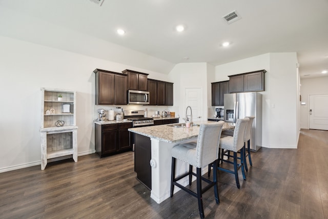 152 Whitetail Way, Caddo Mills, TX 75135 - kitchen with appliances with stainless steel finishes, a sink, dark brown cabinetry, a center island with sink, and a breakfast bar area